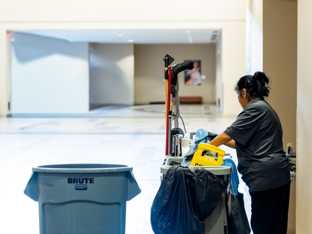 Commercial cleaner with a cleaning trolley in an office building