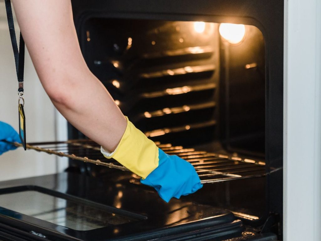 Gloved cleaner cleaning the inside of an oven