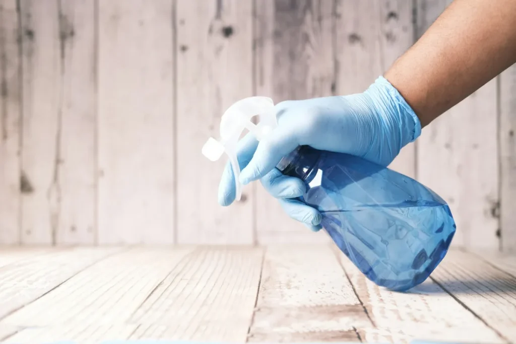 Gloved hand holding a spray bottle, ready for a scheduled clean
